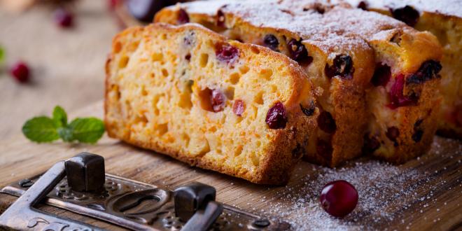 Homemade Pumpkin Cranberry Bread on a cutting board dusted with powdered sugar.