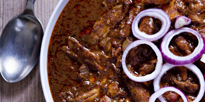 A plate of chicken in brown mole sauce