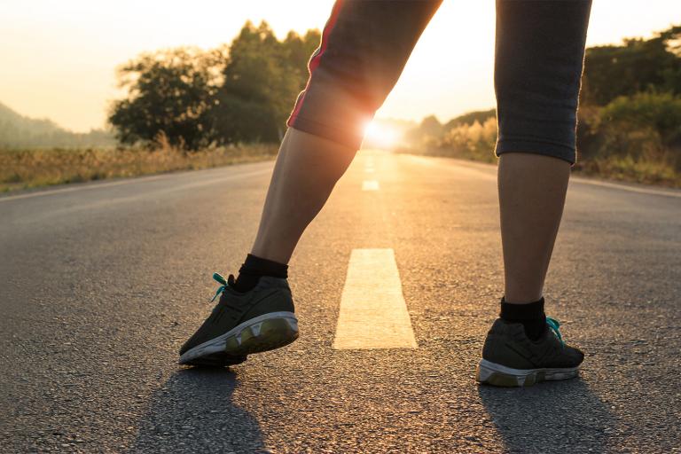 a woman stretching getting ready to run down a long flat stretch of road