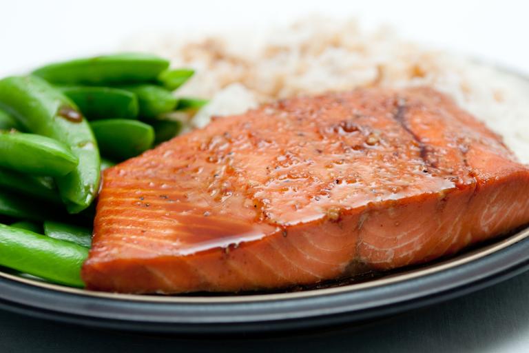 a baked salmon with soy-based glaze, served with snap peas and white rice